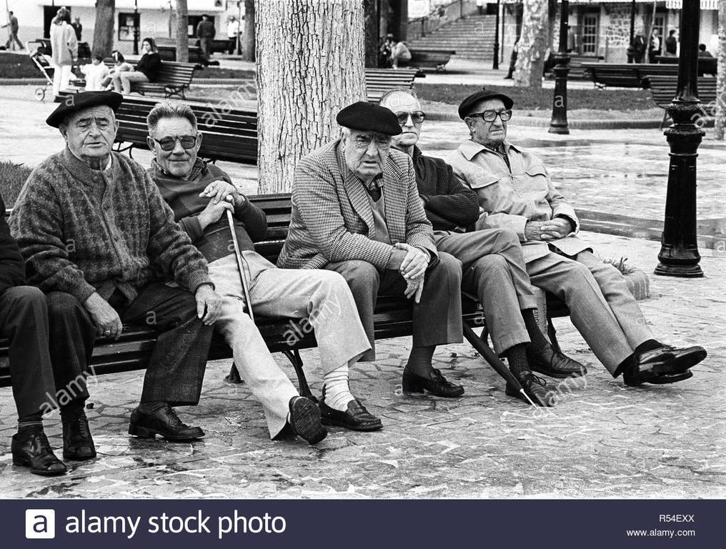 al-basque-berets-sit-on-a-park-bench-in-bermeo-biscay-spain-vintage-black-and-white-image-R54EXX.jpg